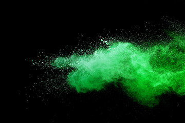 Green powder explosion on black background. Colored cloud. Colorful dust explode. Paint Holi.