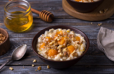 Delicious oatmeal porridge with baked pumpkin, honey and nuts in ceramic bowl on wooden table. healthy homemade breakfast. selective focus