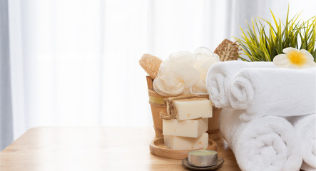 Fototapeta na wymiar White towels,soap,luffa scrub,comb,candle and beautiful frangipani flower in clean white bathroom
