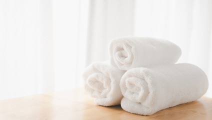 Fototapeta na wymiar Clean white towels fold on wood table with blurred white bathroom background