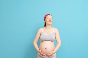 happy young pregnant woman on blue background