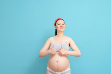 happy young pregnant woman on blue background