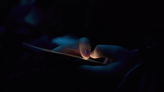 Asian girl typing and scrolling quickly on the smartphone in the twilight