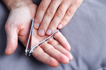 Man cutting nails using nail clipper. Nail clipper in the hands of a man
