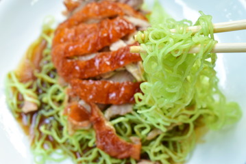 Chinese jade noodles topping slice roasted duck dressing sweet soy sauce picking by chopsticks on plate
