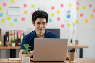 Asian young business man in casual working with laptop in modern office or co-working space,Business Startup Concept