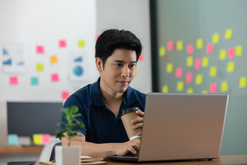 Asian young business man in casual working with laptop in modern office or co-working space,Business Startup Concept