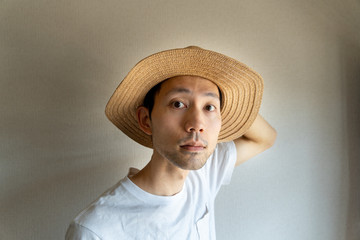 鏡を見ながら麦わら帽子を調整する日本人男性
