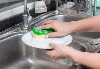 woman’s hand washing dish in the kitchen sink