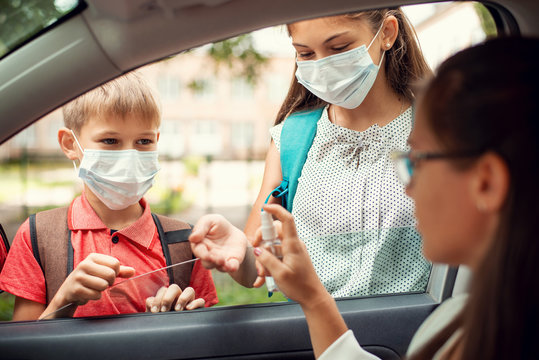 Mother helps her two children to sanitize their hands before going to school. Children in face masks after Covid-19 quarantine and lockdown. Back to school. - Powered by Adobe