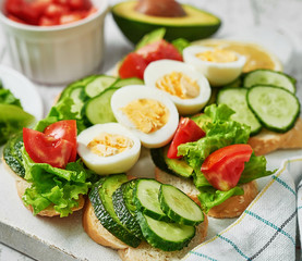 Grain bread sandwiches for breakfast, snacks toasts avocados, eggs, tomatoes, cucumbers. Keto diet. Healthy eating and food, dieting, vegan vegetarian, cleansing. Delicious breakfast or lunch