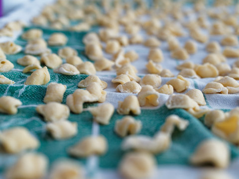 Dinner Time At Home With The Family. On A Tablecloth Numerous Orecchiette, A Typical Product Of Southern Italian Cuisine.