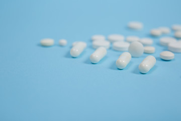 White medical pills on blue background.