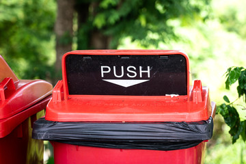 ๋A red plastic junk trash container with sign for pushing object hole. Close-up and Selective focus junk's cover. 