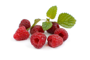 Several ripe juicy raspberries and mint leaf on a white background.