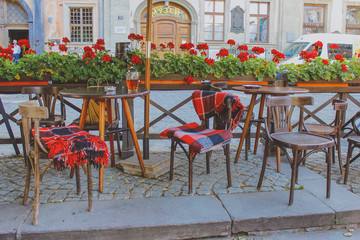Fototapeta na wymiar cafe tables and chairs in the street. blankets on chairs, summer terrace in autumn 