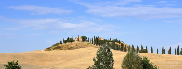 Hügel in der Crete Senesi mit Bauernhof vor strahlend blauem Himmel