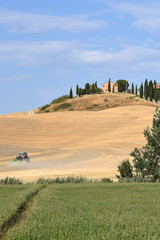 Felder und Traktor am Fuße eines Hügels in der Toskana