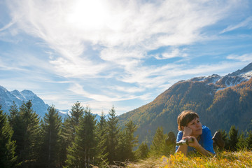 Woman with Binocular Lying Down on Mountainin a Sunny Day in Grisons, Switzerland.
