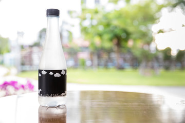 Bottle mineral water on wooden table in restaurant. Water bottle on wood table with summer scene background. plastic bottle of water on wooden table in the park. Healthy and diet concept.