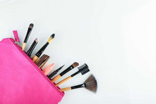 Set Of Makeup Brushes In A Pink Cosmetic Bag Top View On White Background. Concept Of Make Up Artist.