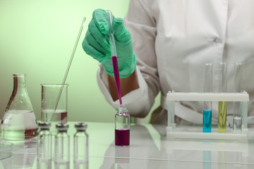 scientist's hands in gloves are conducting chemical experiments in lab close up