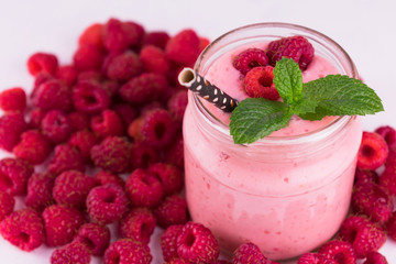 Raspberry smoothie in a jar on a background of fresh raspberries.