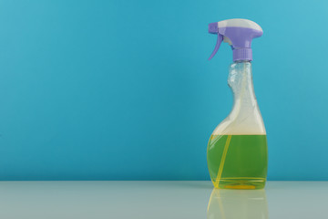 detergent spray bottle on blue background with copy space