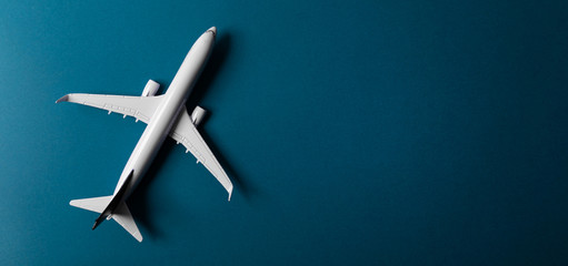 white airplane model on blue paper background with copy space banner. top view