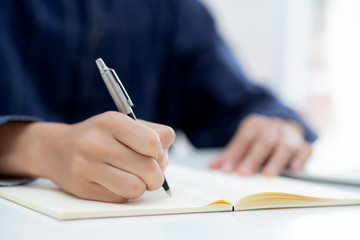 Closeup hand of man writing on notebook with pen on desk, freelance is author, businessman write on notepad on table, book, letter and report, finance and document, business or education concept.