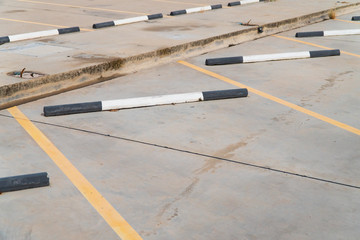 Fototapeta premium Empty car parking lot with black and white concrete car stopper and yellow line.