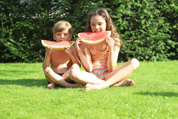 Naklejka na ściany i meble Kinder essen eine Wassermelone im Garten