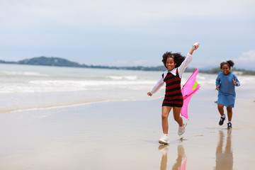 Two African girl enjoy playing kite on the beach.