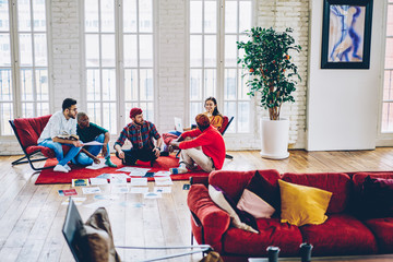 Diverse team of young professional people communicating for discussing strategy of productive collaborative process sitting in stylish loft interior, intelligent students teamworking on course work