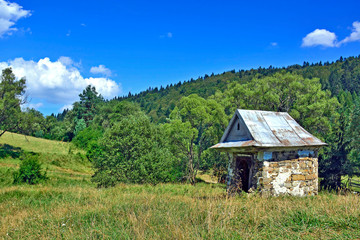 Wayside old stone chapel in summer sunny day, Czarne village, Low Beskids, Poland