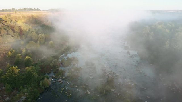 Morning river with rapids. Flying the copter through the morning fog over the river. View from the drone to the misty river.  River rapids foggy. Forest river flow.