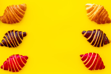 Frame of croissants - fresh bakery on yellow background. Top view