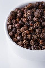 fragrant black pepper on white acrylic background