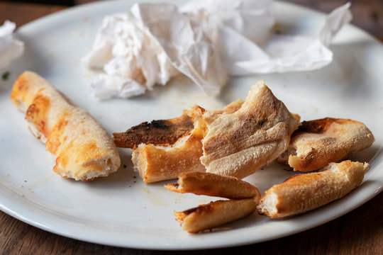 Remainders of pizza and used napkins on a white plate.