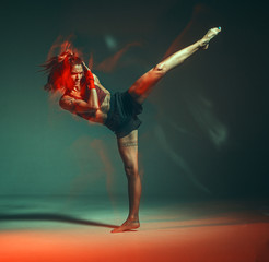 Cool female fighter practicing kicks in studio in neon light. Mixed martial arts poster. Long exposure shot