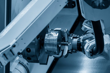 Fototapeta na wymiar The hi-technology CNC lathe machine operation with gripping robotic system.The cobot operation concept in automotive parts manufacturing process by robotic system.