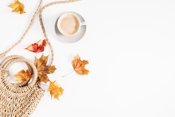 Autumn creative composition. Dry leaves, straw bag and cup of coffee on white background. Fall concept. Autumn background. Flat lay, top view, copy space
