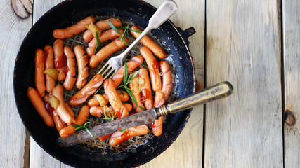 Selective focus. Fried sausages with a crispy crust. Beer snack. German spiced sausages in a frying pan.