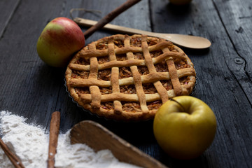 Homemade lattice Apple pie with cinnamon on an old textured wooden background
