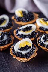 delicious snack tartlets on dark stone background