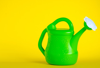 Green watering can garden on yellow background
