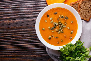 pumpkin carrot cream soup on rustic wooden background