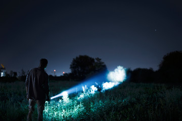 Person with flashlight at night - obrazy, fototapety, plakaty