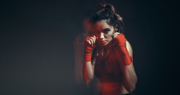 Pretty female fighter in boxing bandages trains in studio in neon light. Mixed martial arts poster. Long exposure shot