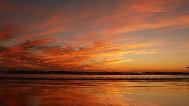 California summertime beach aesthetic, golden sunset. Vivid dramatic clouds over pacific ocean waves. Santa Monica popular resort, Los Angeles CA USA. Atmospheric moody purple evening sundown in LA.